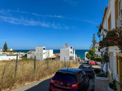 a street with cars parked in front of buildings and the ocean at Beach Retreat Steps from the Ocean #1953 in Luz