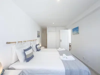 a white bedroom with two beds and a table at Beach Retreat Steps from the Ocean #1953 in Luz