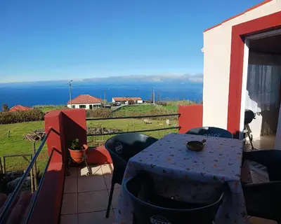 a table on a balcony with a view of the ocean at Achadas da Cruz Farm House in Achadas da Cruz