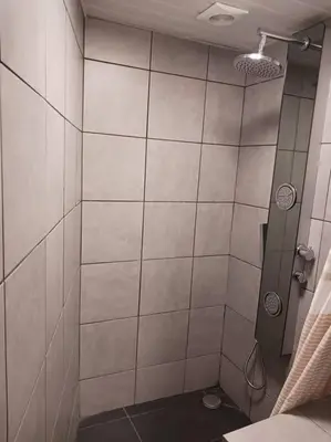 a bathroom with a shower with white tiles at Achadas da Cruz Farm House in Achadas da Cruz