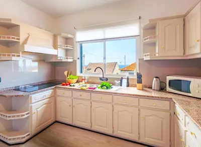 a kitchen with white cabinets and a window at Lighthouse view- POOL VILLA in Porto Moniz