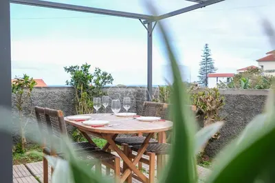 a wooden table with wine glasses on a patio at Moniz Centro I in Porto Moniz