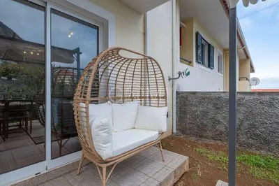 a wicker chair with pillows sitting on a patio at Moniz Centro I in Porto Moniz