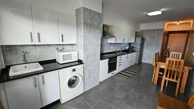 a kitchen with white cabinets and a washer and dryer at Garajau Paradise Apartment in Caniço