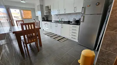 a kitchen with white cabinets and a stainless steel refrigerator at Garajau Paradise Apartment in Caniço