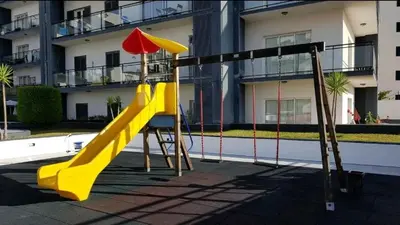 a playground with a slide and an umbrella at Garajau Paradise Apartment in Caniço