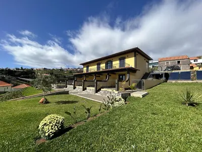 a large yellow house with a green yard at Quinta Das Rosas 5 in Estreito da Calheta
