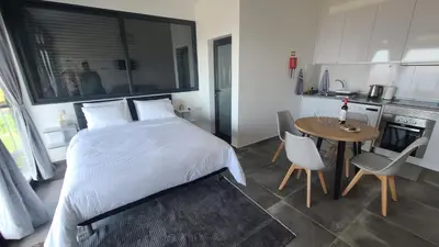 a bedroom with a bed and a table and a kitchen at Quinta Das Rosas 5 in Estreito da Calheta
