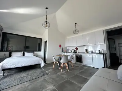 a bedroom with a bed and a table and a kitchen at Quinta Das Rosas 5 in Estreito da Calheta