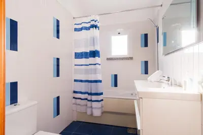 a white bathroom with a sink and a shower curtain at GuestReady - TiClara Villa & Studio in Caniço