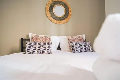 a bedroom with a white bed with pillows and a mirror at GuestReady - TiClara Villa & Studio in Caniço