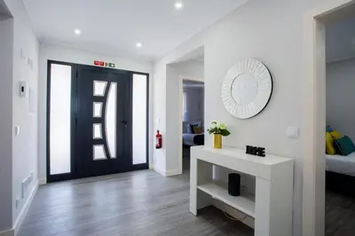 a white living room with a black door and a mirror at Pena View Villa in Santa Cruz
