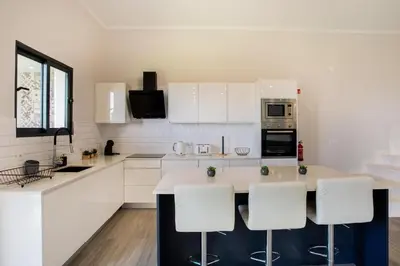 a kitchen with white cabinets and a island with bar stools at Pena View Villa in Santa Cruz