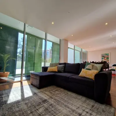 a living room with a black couch and some windows at Upscale, spacious & peacefull 3-bedroom apartment in Funchal