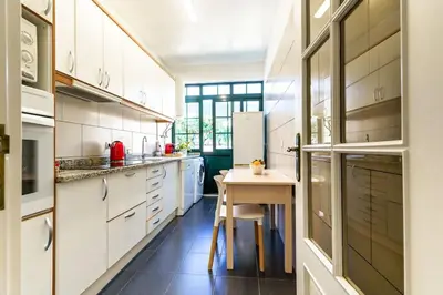 a kitchen with white cabinets and a table in it at Enjoy the city center at fully equipped 2 BR 5 Min walk to beach & market in Funchal
