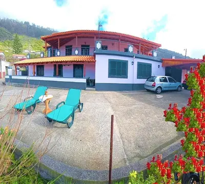 a house with two chairs and a table in a parking lot at The funny and Relax apartment with terrace & view in Arco da Calheta
