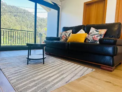 a living room with a black leather couch and a table at BoaVista- 2 bed house -COSY PANORAMIC -SEA - MOUNTAIN VIEW in Campanário