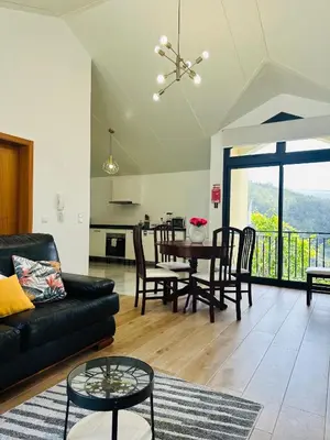 a living room with a black couch and a table at BoaVista- 2 bed house -COSY PANORAMIC -SEA - MOUNTAIN VIEW in Campanário