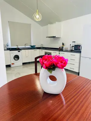 a white vase with red roses sitting on a table at BoaVista- 2 bed house -COSY PANORAMIC -SEA - MOUNTAIN VIEW in Campanário