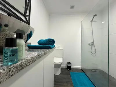a bathroom with a shower and a blue towel on a counter at Center Funchal - Rooms For Rent in Funchal