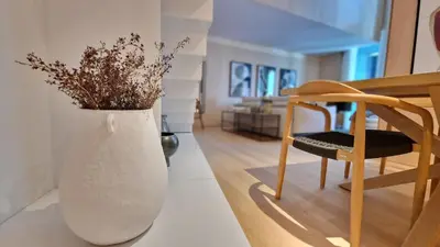 a white vase with flowers in it next to a chair at The Urban Retreat by LovelyStay in Funchal