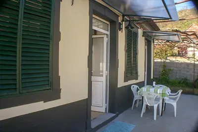 a table and chairs sitting on a porch with a window at Typical Farm Apartment in Arco da Calheta