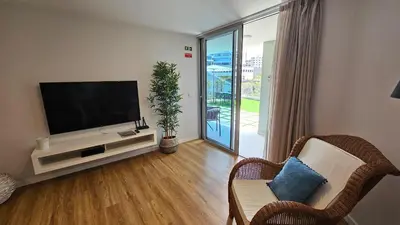 a living room with a flat screen tv and a balcony at Magnólia Residence in Funchal