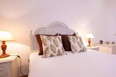 a bedroom with a white bed with pillows and two lamps at Casa Fonte do Serrado in Caniçal