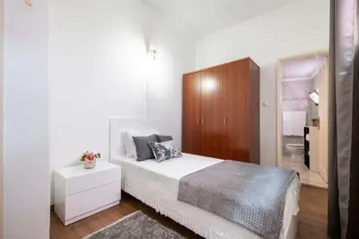 a white bedroom with a bed and a wooden cabinet at Casa Fonte do Serrado in Caniçal