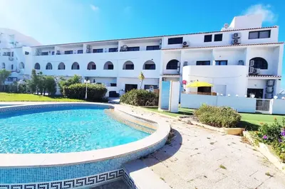 a building with a swimming pool in front of a building at Sun & Fun in Sagres in Sagres