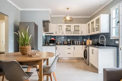 a kitchen with white cabinets and a wooden table and chairs at Villa Pedreiro in Funchal
