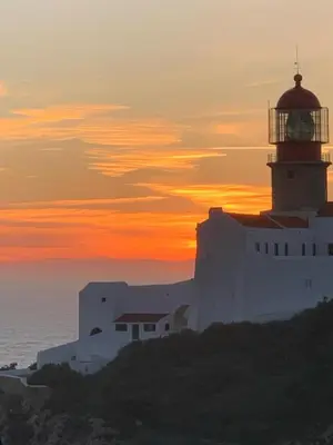 a lighthouse on a cliff with the sunset in the background at Casa Primeira in Vila do Bispo