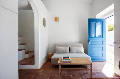a bedroom with a bed and a table with a blue door at Casa Primeira in Vila do Bispo
