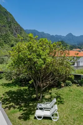 a group of white lounge chairs under a tree at São Vicente Guest House in São Vicente