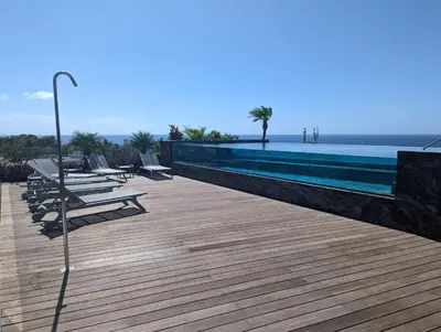 a row of lounge chairs sitting on a wooden deck near a swimming pool at Chic Two-Bedroom En Suite in Central Town - Savoy Residence in Funchal