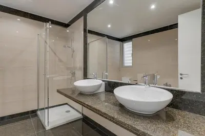 a bathroom with two sinks and a glass shower at Luxurious Ocean and Sunset Views Family Haven with 3 En-Suite Bedrooms and Pool in Funchal
