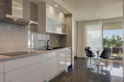 a kitchen with white cabinets and a table with chairs at Luxurious Ocean and Sunset Views Family Haven with 3 En-Suite Bedrooms and Pool in Funchal