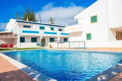 a house with a swimming pool in front of a building at APARTAMENTOS OASIS BEACh in Lagos