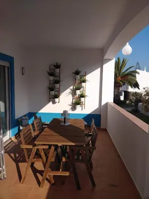 a wooden table and chairs on a balcony at APARTAMENTOS OASIS BEACh in Lagos