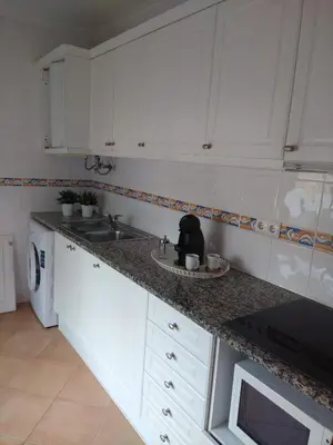 a kitchen with white cabinets and a sink at APARTAMENTOS OASIS BEACh in Lagos