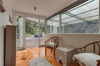 a room with a bed and a chair and sliding glass doors at Villa Natural Oasis with panoramic view & bio-diverse 9 950m2 garden in Funchal