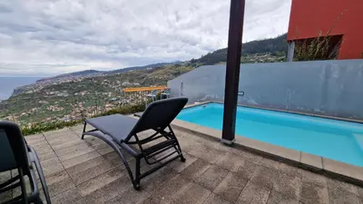 a chair sitting on a balcony with a swimming pool at The Red Hot Chill House by LovelyStay in Arco da Calheta