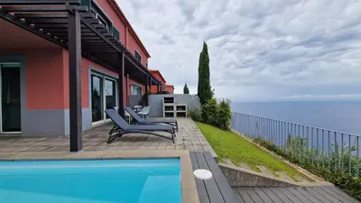 a house with a swimming pool next to the ocean at The Red Hot Chill House by LovelyStay in Arco da Calheta