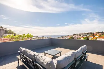 a balcony with a couch and a table on a roof at Balcoes in Funchal