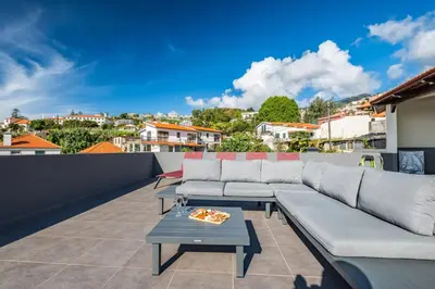 a rooftop patio with a couch and a table at Balcoes in Funchal