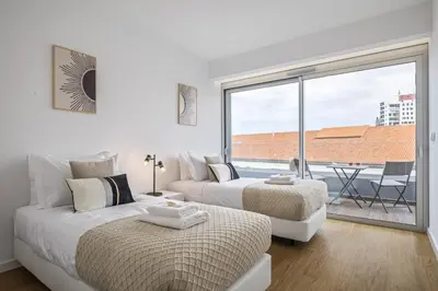 a white bedroom with two beds and a large window at Penthouse A Fabrica by Homie in Funchal