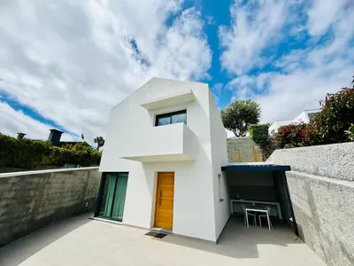 a white house with a brown door and a wall at Casa Victória in Funchal