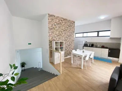 a living room with a white table and a kitchen at Machico flat center near beach w parking in Machico