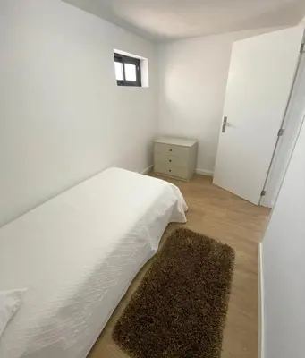 a white bedroom with a bed and a rug at Machico flat center near beach w parking in Machico