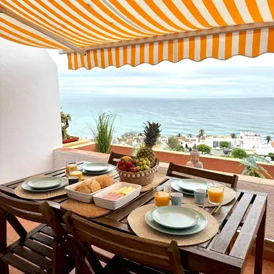 a table with plates of food on a balcony with the beach at Luz Ocean View Apartment in Luz